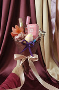 Bouquet of flowers with a pink box and makeup items against a red patterned background